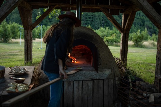 Chef putting food into a wood-fired oven.